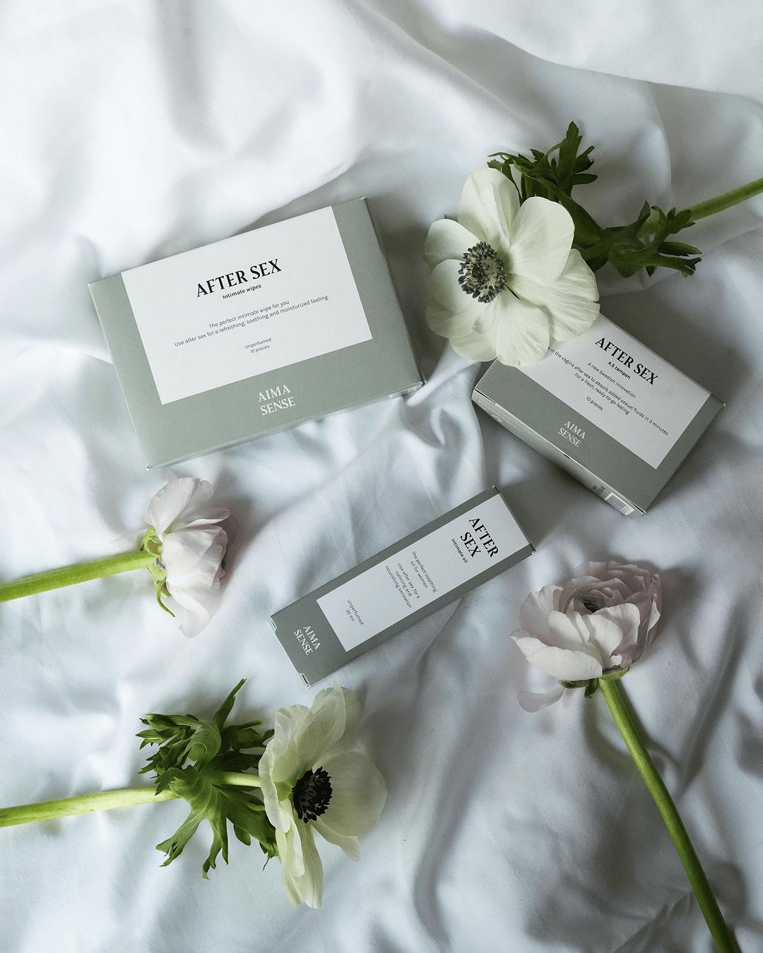 Aima Sense After Sex wipes, tampong och olja liggandes med vita blommor